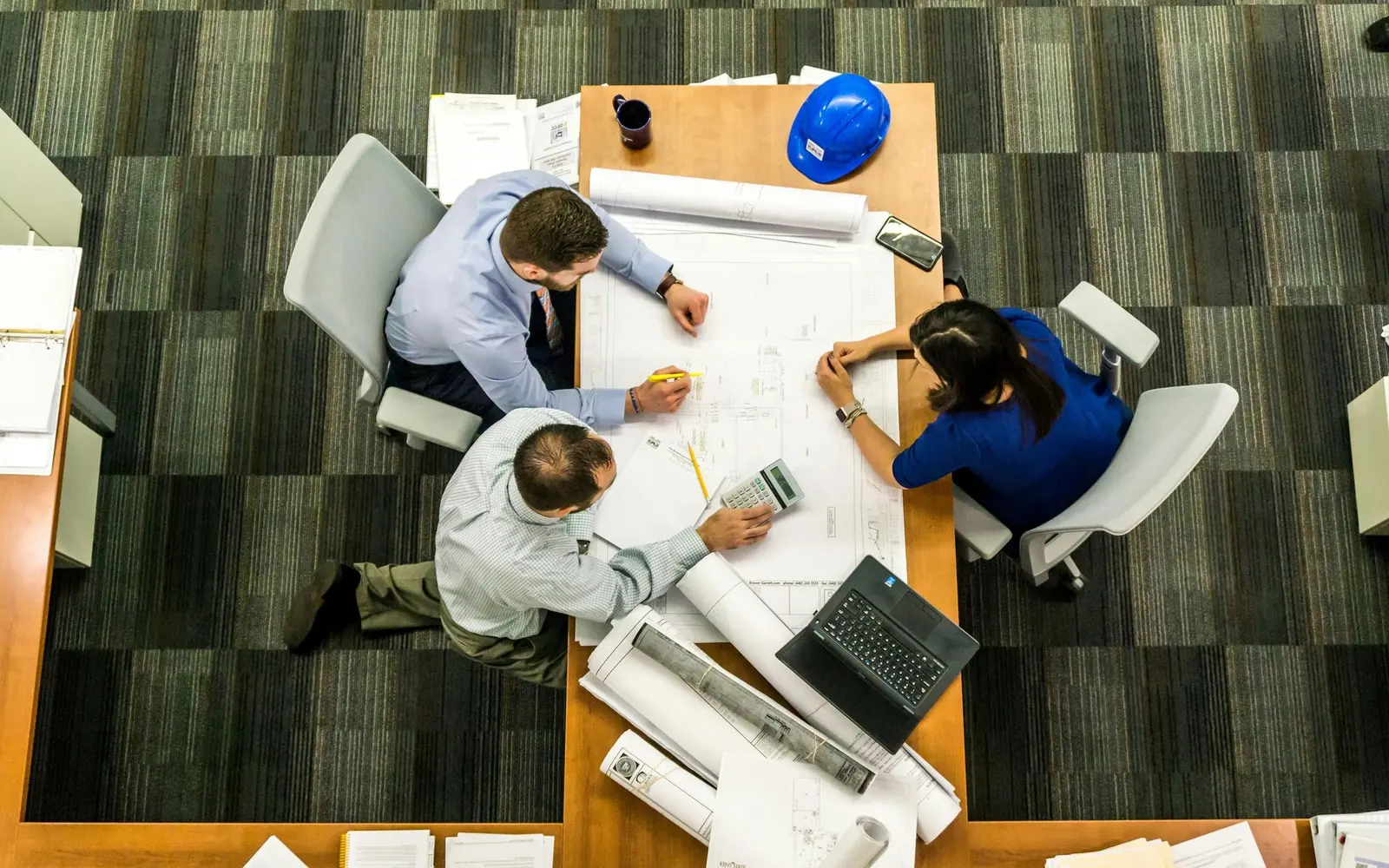 Three people around a table discussing plans