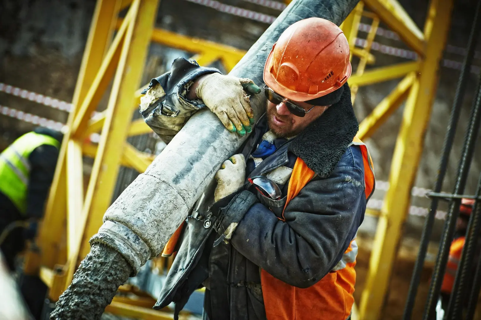 Construction worker carrying a heavy pipe on site